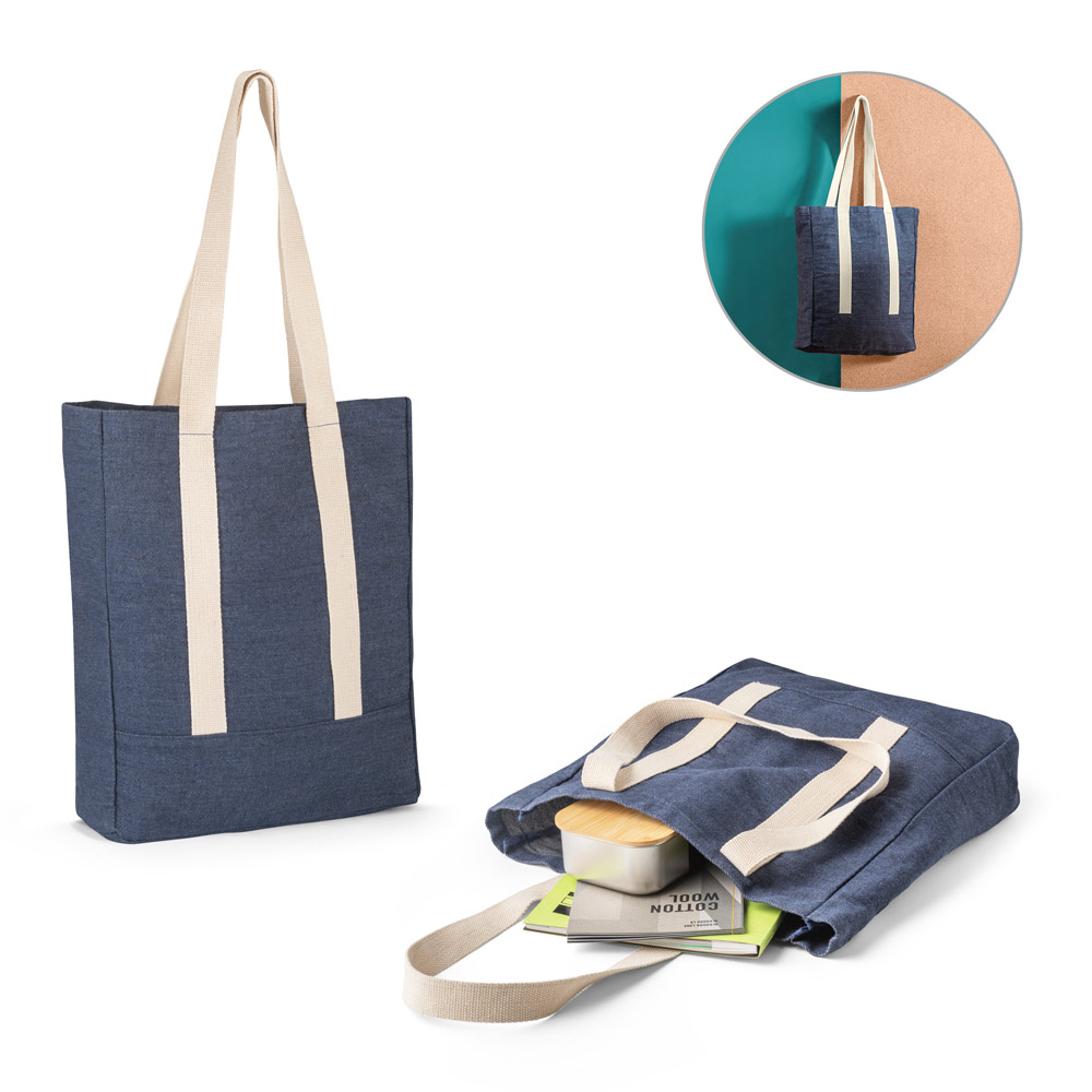Bolsa tote de tela azul marino con asas beige y contenido (libros y fiambrera) parcialmente visible.